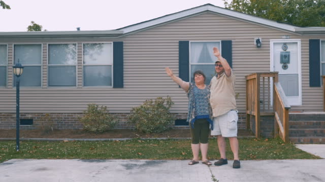 Heavy-couple-waving-and-saying-goodbye-to-someone-in-front-of-their-home