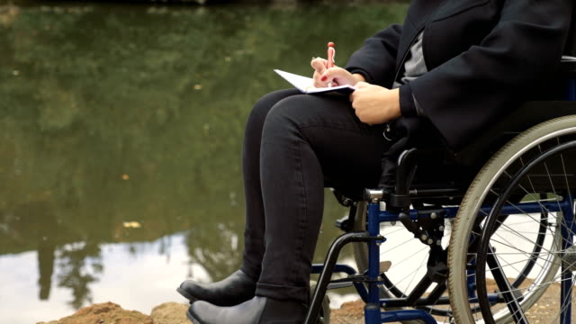 hautnah-auf-traurige-und-einsame-Frau-im-Rollstuhl-schreibt-Tagebuch