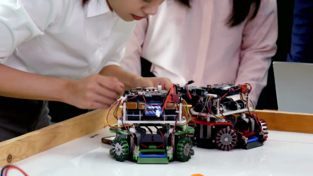 Teenage-Engineering-Maschine-in-Werkstatt-reparieren.-Weibliche-Engineering-Robotik-Prototyp-im-Labor-mit-Team-machen.-4K-Auflösung.