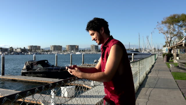 Carefree-young-man-taking-pictures-at-a-marina
