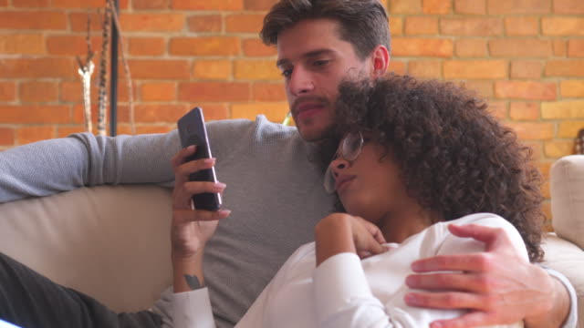Couple-using-mobile-phone-on-sofa-at-home