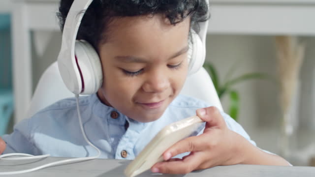 Kleiner-Junge-im-Kopfhörer-genießen-Sie-Musik-auf-Smartphone