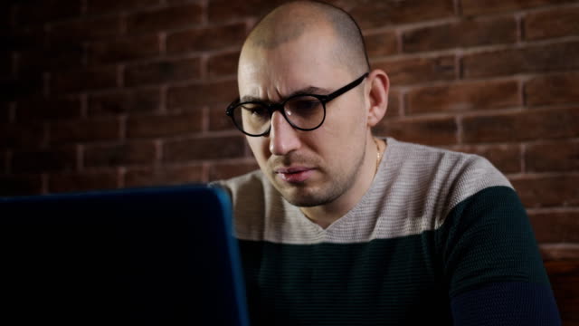 Passionate-man-with-glasses-working-with-laptop-in-the-office.-A-male-writer-is-typing-text-on-laptop-keyboard,-close-up.