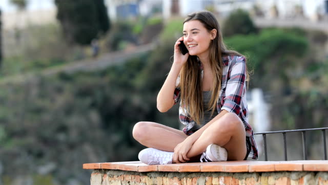 Teenager-Mädchen-am-Telefon-sitzt-auf-einem-Felsvorsprung-aufrufen