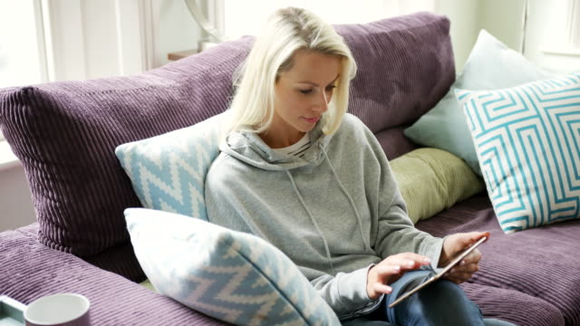 Schöne-blonde-Dame-entspannen-zu-Hause-mit-Tablet-PC