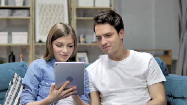Joven-pareja-navegando-por-Internet-en-Tablet-mientras-relajante-en-el-sofá