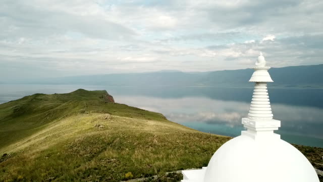 Aerial-Close-Unique-Buddhist-stupa-historic-monument-symbol-spire-top-mystical-ritual-costal-Ogoi-Island-Lake-Baikal-rock-Burkhan-landscape-mountains-Shamanic-worship.-Drone-Around