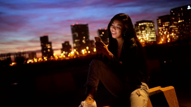 Hipster-asiatische-Teenager-Mädchen-im-Chat-online-per-Smartphone-in-Stadt