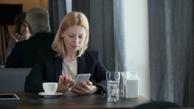 Senior-Businesswoman-Using-Smartphone-in-Restaurant