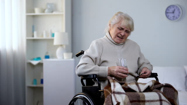 Ältere-Dame-im-Rollstuhl-mit-Schmerzen,-Einnahme-von-Medikamenten,-Pflegeheim