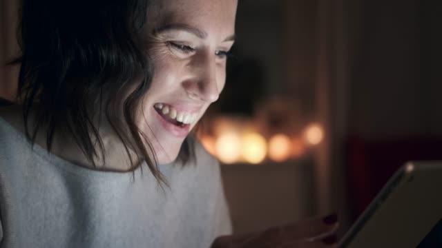 Mujer-sonriente-con-tableta-digital-en-la-noche