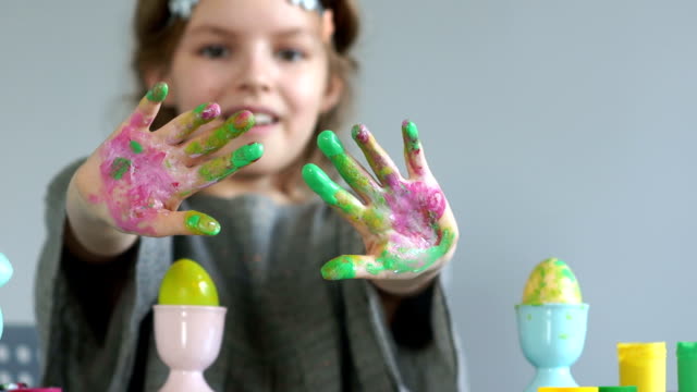 El-cierre-de-las-manos-de-una-niña-sucia-en-pintura-multicolor