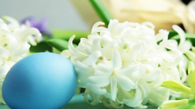 Blue-easter-eggs,-candles-and-white-hyacinth-on-blue-concrete-table-surface-background,-copy-space-for-you-text.-Festive-background.-Happy-Easter-greeting-card.