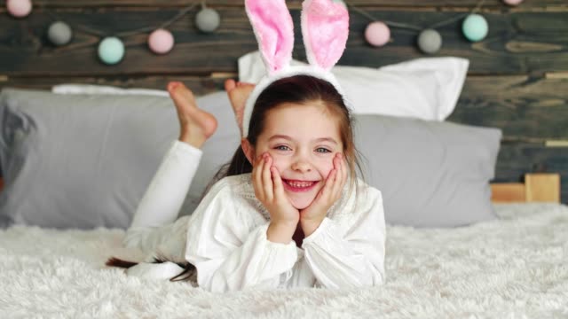 Smiling-girl-with-bunny-ears-lying-on-the-bed