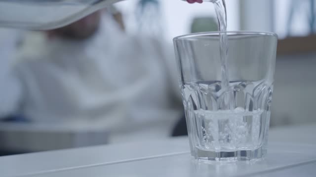 Angenehmer-Kellner-gießt-Trinkwasser-in-ein-Glas,-bevor-er-Hauptgericht-bringt