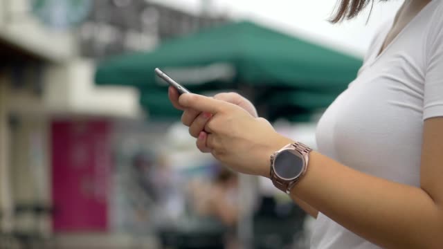 Mujer-asiática-usando-teléfono-inteligente-al-aire-libre-parque-público.-Cámara-lenta-de-cerca.-Buscar-en-Internet,-tecnología-en-línea.