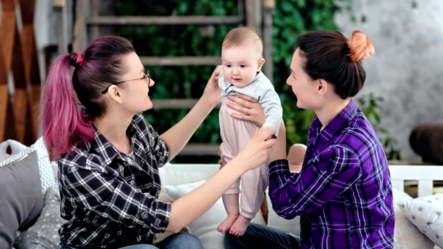 Same-sex-couple-family-smiling-and-playing-with-little-cute-baby-at-home