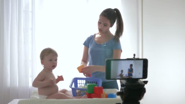 Videoblog-streaming-en-vivo,-lindo-bebé-niño-con-mamá-jugado-por-juguetes-educativos-y-la-filmación-de-nuevo-episodio-para-Vlog-en-streaming-en-vivo-en-el-teléfono-inteligente-para-los-suscriptores-en-las-redes-sociales