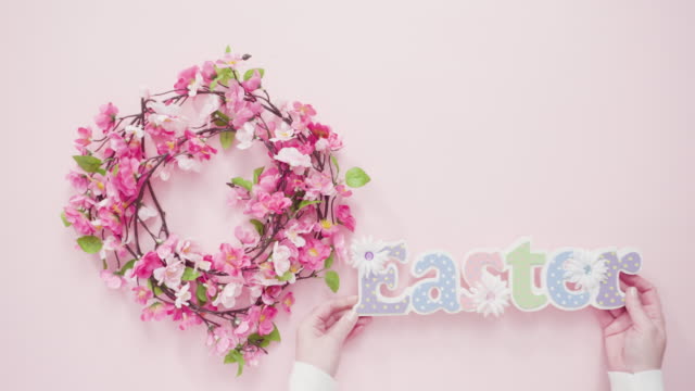 Ostern-Zeichen-mit-Blumenkranz-auf-einem-rosa-Hintergrund.