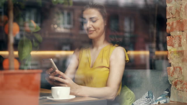 Attraktive-junge-Dame-mit-Smartphone-im-Café-entspannen-mit-Gadget-und-Kaffee