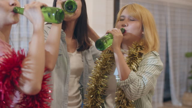 Group-of-Asian-women-party-at-home,-female-drinking-beer-dancing-and-singing-having-funny-together-in-living-room-in-night.-Teenager-young-friends-play-game,-celebrate-holiday-concept.-Slow-motion.