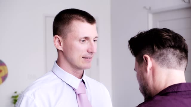Gay-man-help-his-partner-putting-on-tie-for-job-interview.-Kiss-each-other.