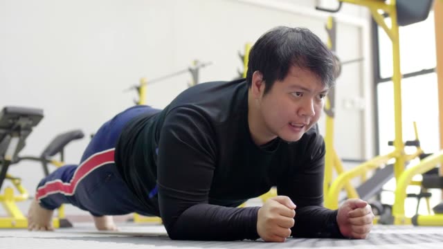 Hombre-asiático-tratando-de-hacer-ejercicio-con-mancuerna-en-el-gimnasio,-estilo-de-vida-saludable,-deseo-de-pérdida-de-peso