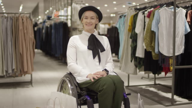 Glückliche-Frau-im-Rollstuhl-posiert-in-Kleidung-Store