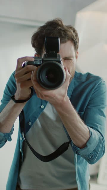Portrait-of-the-Handsome-Photographer-Holding-State-of-the-Art-Camera-Ready-to-Take-Pictures-with-Softboxes-Lighting-in-Background.-Vertical-Screen-Orientation-Video-9:16