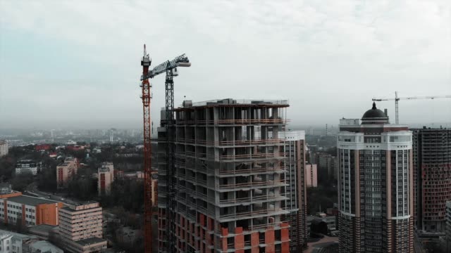 Brick-and-concrete-at-construction-works.-Aerial-drone-view-of-high-rise-residential-complex-construction.-High-crane-near-unfinished-building