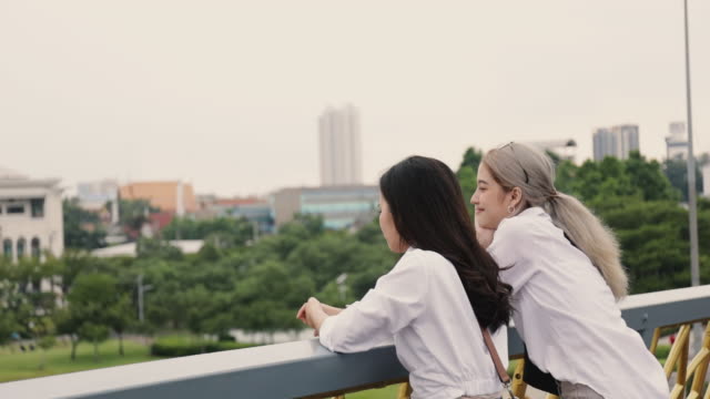 Parejas-lesbianas-asiáticas-disfrutando-viajando-y-hablan-mientras-están-de-pie-en-el-puente.