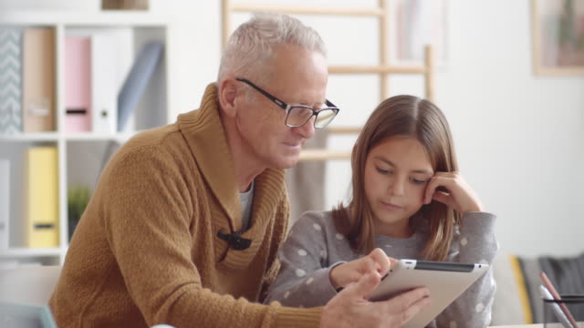 Senior-mit-modernen-Tablet-mit-Hilfe-von-Enkelin