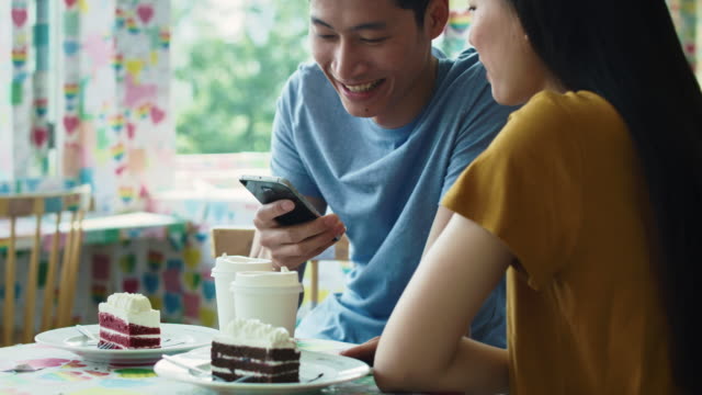 Handheld-view-of-couple-using-mobile-phone-at-cafe