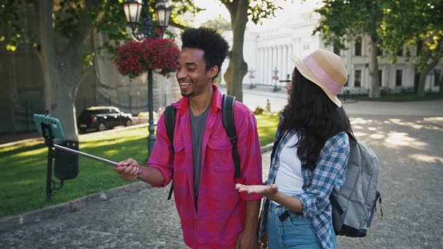 Afro-amerikanische-männliche-und-weibliche-Aufnahme-video-für-Abonnenten-auf-smartphone,-während-zu-Fuß-entlang-der-Stadtstraße