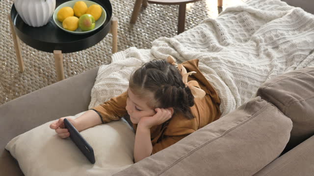 Little-girl-with-bows-and-plaid-watches-cartoons-on-phone