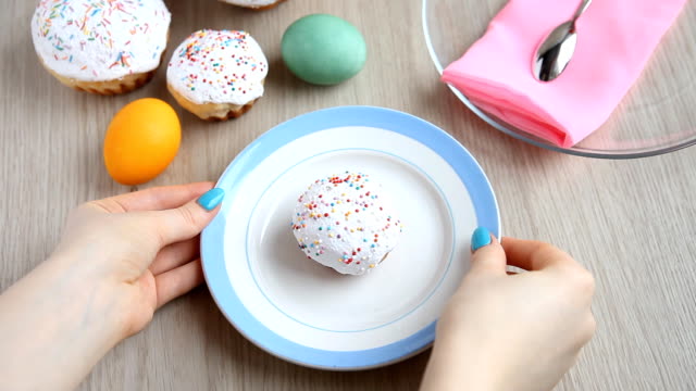 Hands-take-away-from-the-table-a-plate-with-a-Easter-cake-with-white-icing.