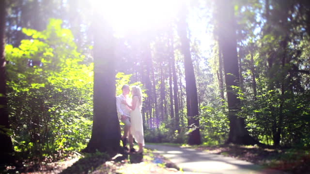 Man-and-woman-in-park-or-forest-among-trees.-Having-a-date-in-nature-tilt-shift.-Young-couple-embrace-leaning-on-a-tree.-Romantic-memories-tenderness-relationship-love-story