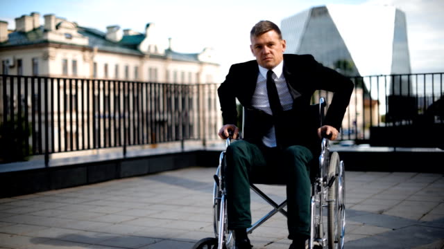 Handicapped-businessman-trying-to-get-up-from-wheelchair-outdoor