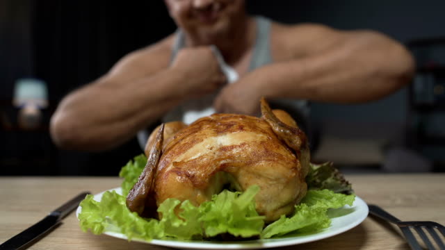 Fat-man-preparing-to-eat-greasy-fried-chicken,-holding-knife-and-fork,-close-up