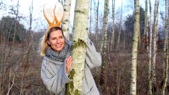 Cinemagraph-of-blond-woman-with-bunny-ears-looking-from-behind-a-tree