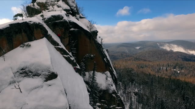 Luftaufnahme-von-einem-Kletterer-Klettern-steile-Klippen-bei-einem-sonnigen-Wintertag.