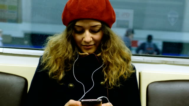 Schöne-kaukasischen-Frau-mit-Kopfhörern-mit-Handy-in-der-u-Bahn