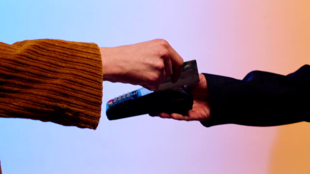 Close-up-of-customer-paying-by-credit-card.-Stock.-Payment-for-purchase-by-Bank-transfer-on-a-colored-background