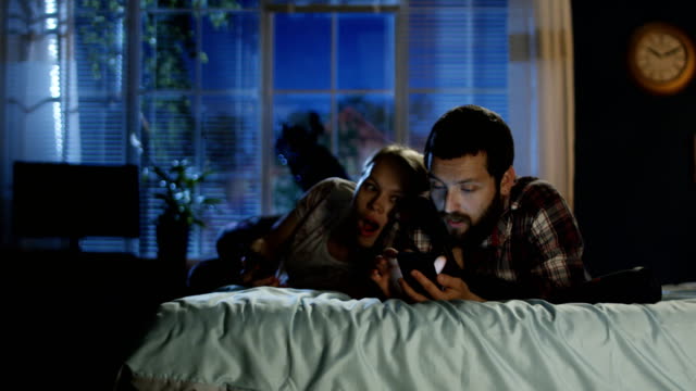 Young-couple-surfing-smartphone-on-bed