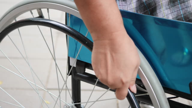 Close-up-Hand-mit-Rollstuhl-Patienten-alleine-fahren