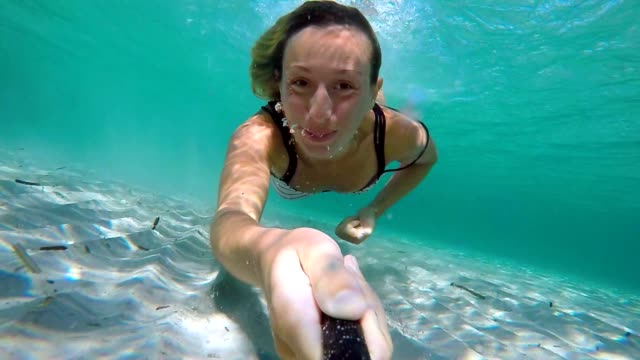 Selfie-portrait-of-young-woman-underwater-swimming-in-clear-blue-water-enjoying-vacations-in-Italy-Sardinia