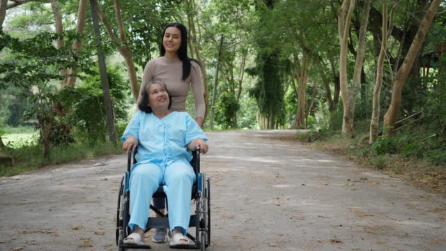 Mujer-mayor-con-su-hija-empujando-la-silla-de-ruedas-por-el-Parque