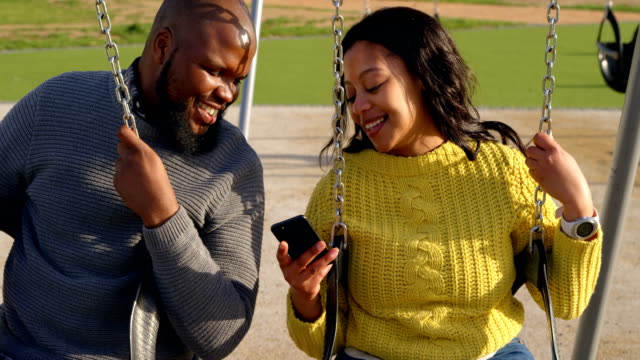 Happy-couple-using-mobile-phone-in-the-park-on-a-sunny-day-4k
