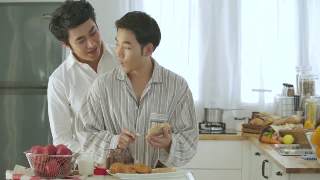 Attraktive-junge-asiatische-Schwule-paar-frühstücken-in-Küche.-Mann-Kochen-Frühstück-für-ihn-Freund-mit-attraktiven-Lächeln-auf-den-Lippen.-Menschen-mit-Homosexuell,-Homosexuell,-Beziehung-Konzept.