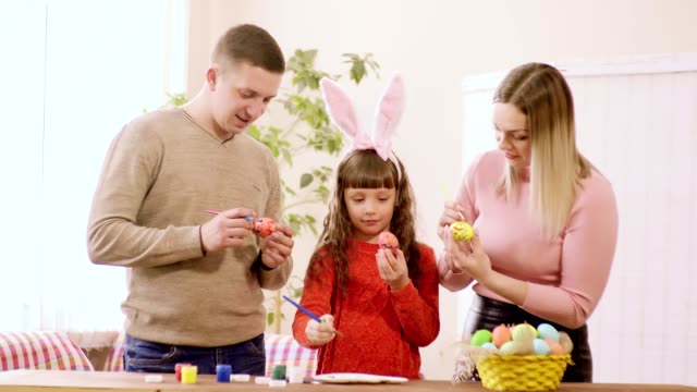 familia-de-padre,-esposa-e-hijo-decoran-los-huevos-de-Pascua.